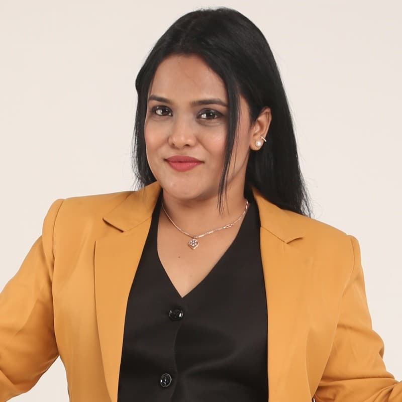 Devaki, founder of Own The Room, speaking into a podcast microphone